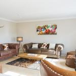 Wohnzimmer mit zwei Ledersofas, Holztisch und Wandbild mit Rindern.