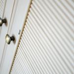 Weißer Schrank mit zwei Messinggriffen und gerippter Front