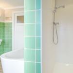 Bad mit Dusche, Badewanne und Waschbecken mit grünen Fliesen