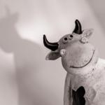 Eine schwarz-weiße Kuhfigur mit Hörnern und einem Lächeln wirft einen Schatten an der Wand.