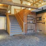 Helle Eingangshalle mit Holztreppe und Pferdestalltüren.