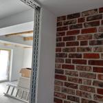 Raum mit sichtbaren Ziegelwand und Baustelle mit Leiter und Karton.