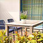 Terrasse mit Holztisch, blauen Stühlen und Lavendel in Topf