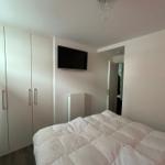 Schlafzimmer mit Bett, Kleiderschrank und Wandfernseher