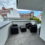 Terrasse mit schwarzer Lounge-Möbelgruppe und Blick auf Gebäude