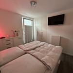 Schlafzimmer mit Doppelbett, Kleiderschrank und Fernseher an der Wand.