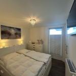 Schlafzimmer mit Doppelbett, Schrank, Fenster und Deckenleuchte.
