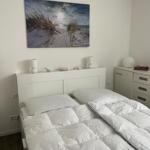 Schlafzimmer mit weißem Bett, Wandbild und Nachttisch