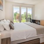 Schlafzimmer mit Bett, Schreibtisch und Balkonansicht