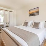 Schlafzimmer mit Doppelbett, Kleiderschrank und Wandbild.