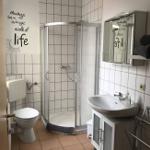 Badezimmer mit Dusche, Waschbecken und Toilette. Wanddekoration mit Motiv.