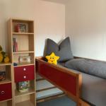 Kinderzimmer mit Bett, Bücherregal und Spielzeug.