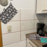 Küchenbereich mit Kaffeemaschine, Handtuch und Pug-Handschuhen an der Wand.
