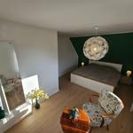 Schlafzimmer mit Bett, Stuhl und Spiegel an der Wand