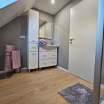 Badezimmer mit Dusche, Waschbecken und Handtuchhalter. Holzfußboden und Spiegelschrank.