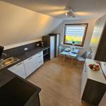 Küche mit Essbereich, Fenster, Holzboden und Küchenschränken.