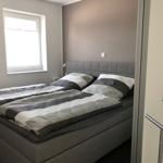 Ein Schlafzimmer mit Doppelbett, Fenster und Wandbild.