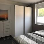 Schlafzimmer mit Bett, Kleiderkabinen und Fenster mit Blick auf Bäume.