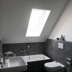 Badezimmer mit Dachfenster, Badewanne, Waschbecken und Toilette.