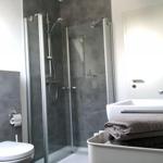 Badezimmer mit Dusche, Waschbecken und Toilette. Handtuch auf Waschbecken.