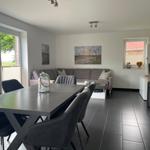 Essbereich mit Tisch und Stühlen, Wohnbereich mit Sofa und Kaminofen.