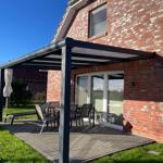 Terrasse mit Sitzgruppe unter Markise neben Haus mit Backsteinwand.