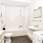 Badezimmer mit Badewanne, Waschmaschine und Toilette.