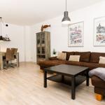 Wohn- und Essbereich mit braunem Sofa, Holzboden und Wandbildern.