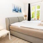Schlafzimmer mit Doppelbett, Fenster und Wandbild mit Segelbooten.