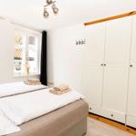 Schlafzimmer mit Doppelbett, weißen Wänden und weißen Schränken. Fenster mit Blick auf Dächer.