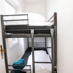 Doppelstockbett mit weißer Bettwäsche und blauen Handtüchern neben einem Fenster.