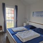 Schlafzimmer mit Doppelbett, Fenster mit Balkon und Wandbild.