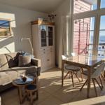 Wohn- und Essbereich mit Blick aufs Meer und Balkon. Möbel aus Holz und Stoff.