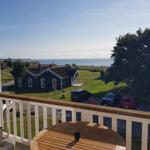 Terrasse mit Tisch, Blick auf Grünfläche, Gebäude und Meer.