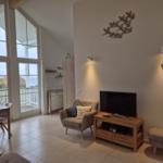 Wohnzimmer mit TV, Sessel und Blick auf Balkon. Wanddekoration und Holzmöbel.