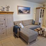 Wohnzimmer mit Sofa, Holzmöbel und Strandbild an der Wand.