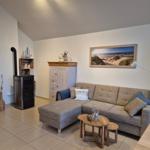 Wohnzimmer mit Sofa, Kaminofen und Wandbild