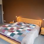 Schlafzimmer mit Holzbett, gemustertem Deckenbezug und Nachttischen mit Lampe.