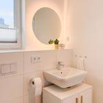 Badezimmer mit Waschbecken, Spiegel und Fenster.