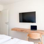 Schlafzimmer mit Bett, Schreibtisch und Fernseher an der Wand