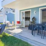 Terrasse mit Sitzgelegenheiten, Grill und Blick in die Küche.