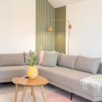Ein Wohnzimmer mit einem grauen Sofa, einem Holztisch und einer Wand mit grünen Streifen.