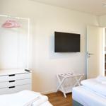 Schlafzimmer mit Bett, Kleiderschrank und Fernseher. Tür führt in Esszimmer.