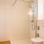 Badezimmer mit Dusche, Toilette und Waschbecken. Fenster mit Jalousie.