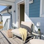 Terrasse mit Liege, Tisch und Pflanzen. Hintergrund: Haus mit Balkon und Garten.