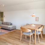 Essbereich mit Holztisch und Stühlen. Wohnbereich mit Sofa und Teppich.