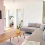 Wohnzimmer mit Sofa, Couchtisch und Fernseher. Blick in Schlafzimmer und Bad.