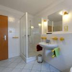 Badezimmer mit Dusche, Waschbecken und Spiegel. Gelbe Halterungen und Handtuchhalter.