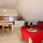 Wohnung mit Küche, Essbereich und Sofa unter Dachschrägen.