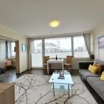 Wohnbereich mit Sofa, Esstisch und Blick auf Balkon.
